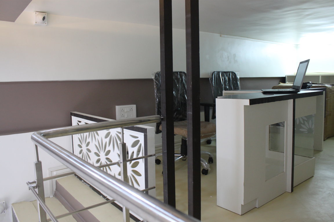 Stair-side coordination desk on the Insight Institute mezzanine, with stainless rails, laser-cut floral balustrade and a laptop workstation
